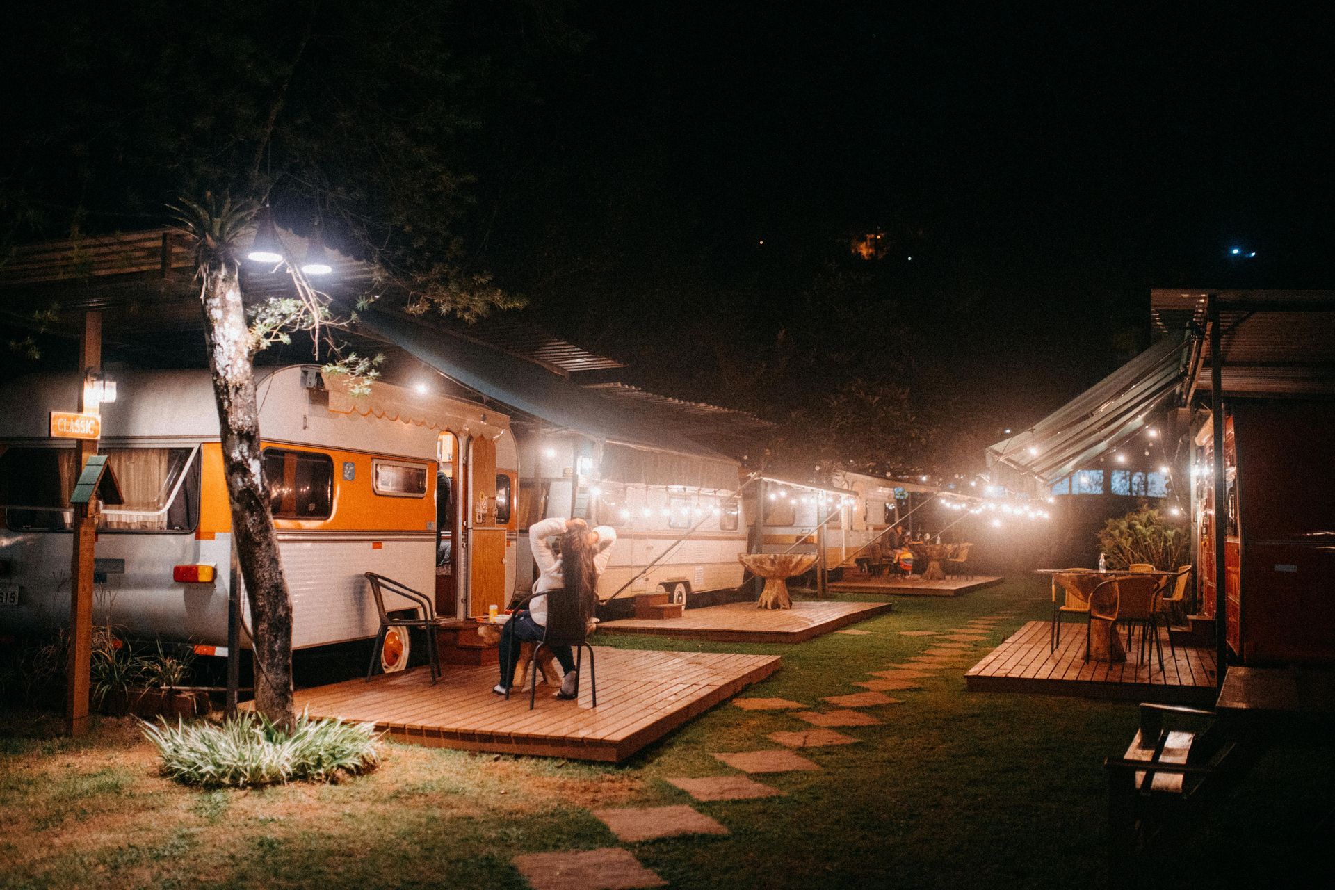 A couple is standing in front of a row of trailers at night.