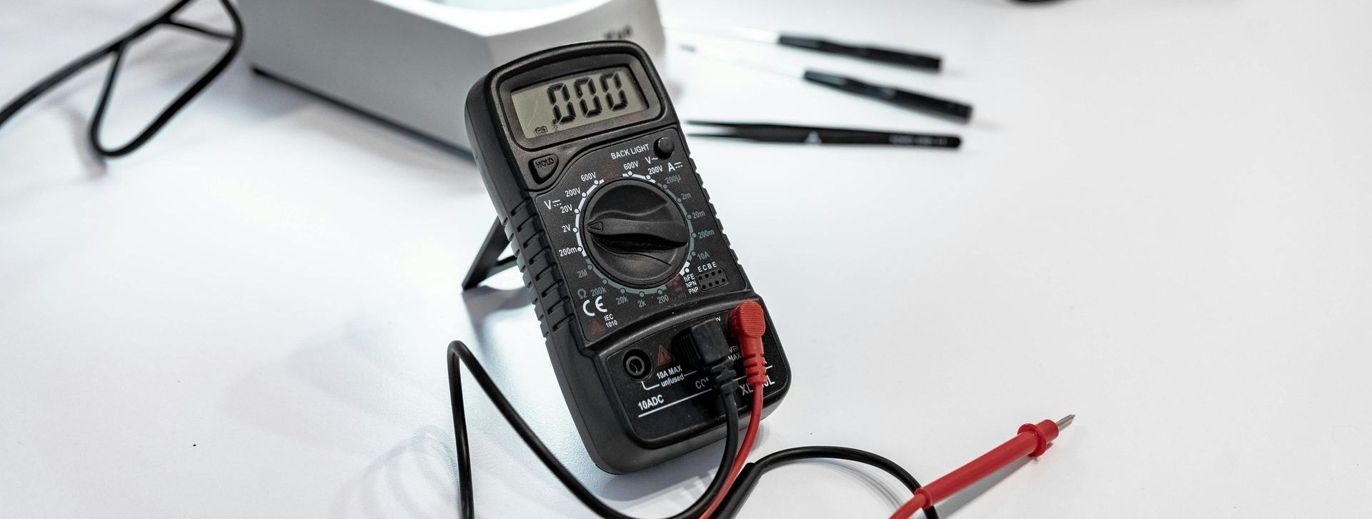 A digital multimeter is sitting on top of a white table.