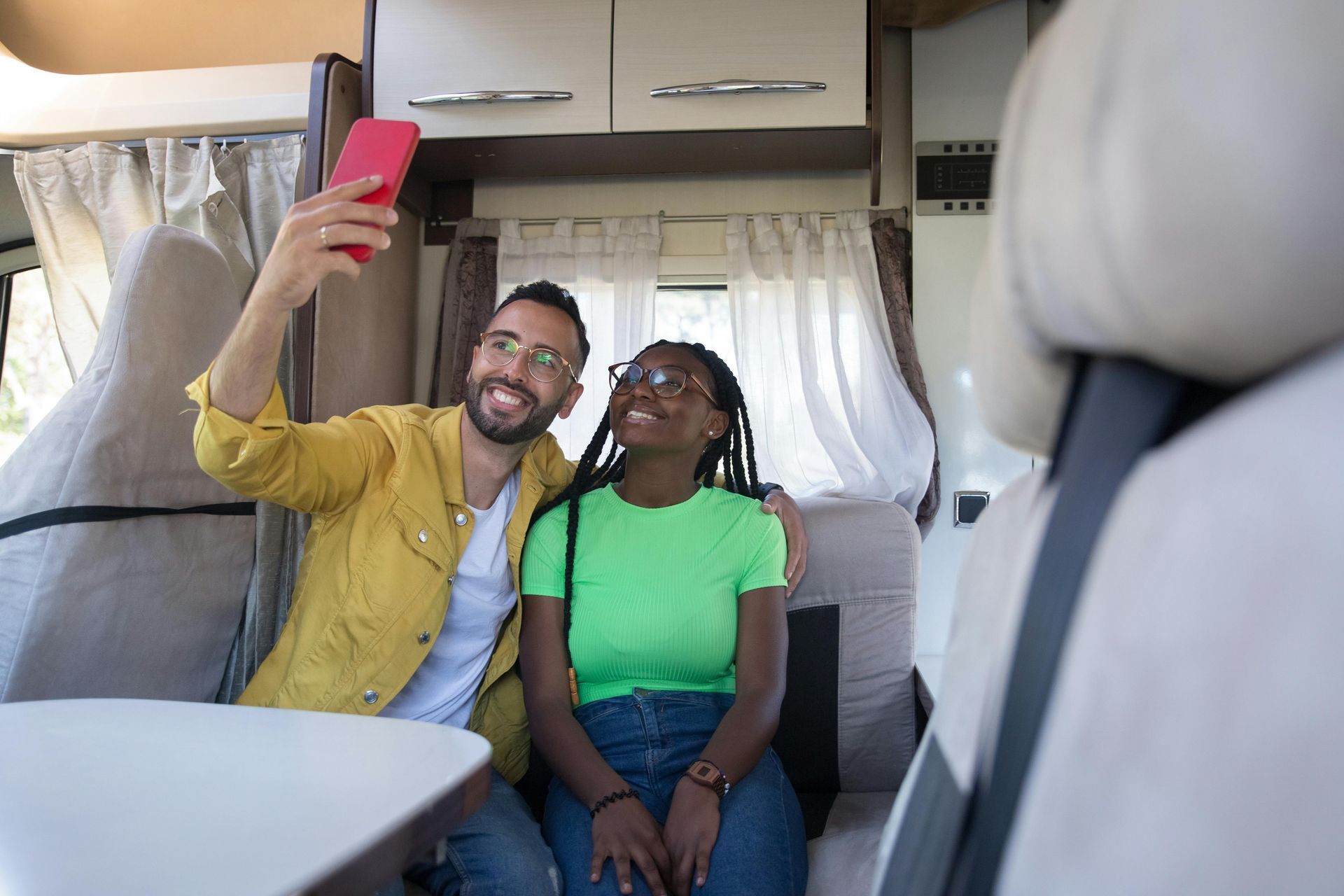 A man and a woman are taking a selfie in a camper van.