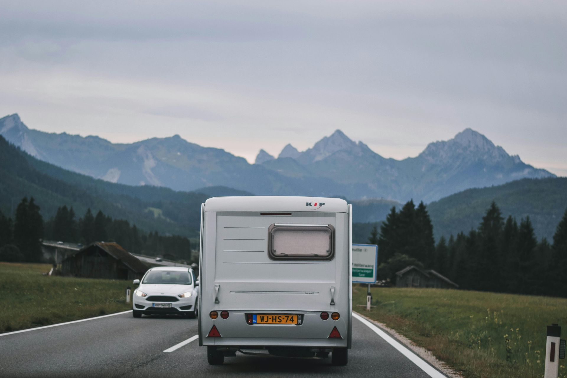 A caravan is driving down a road with mountains in the background.