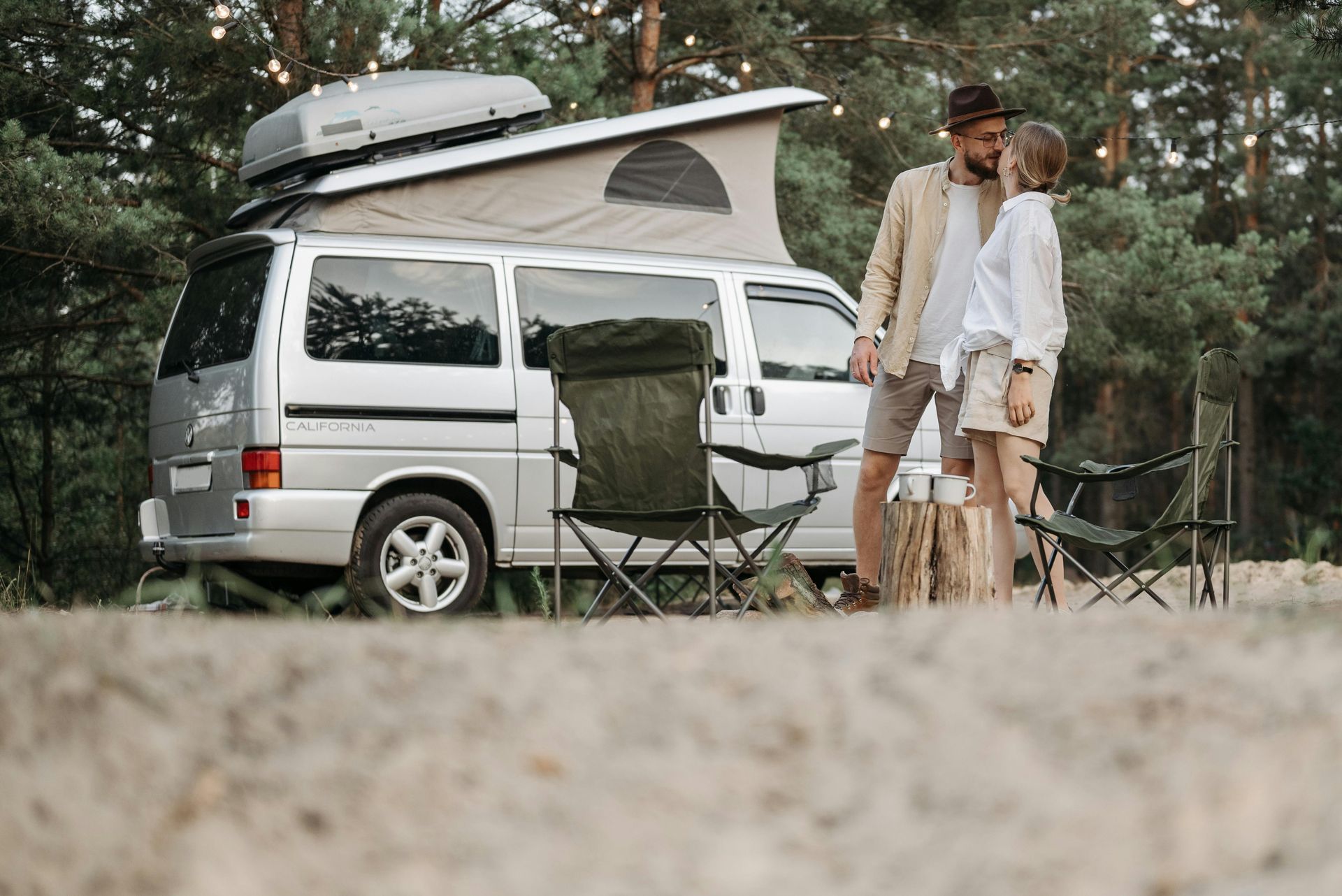 A man and a woman are kissing in front of a camper van.