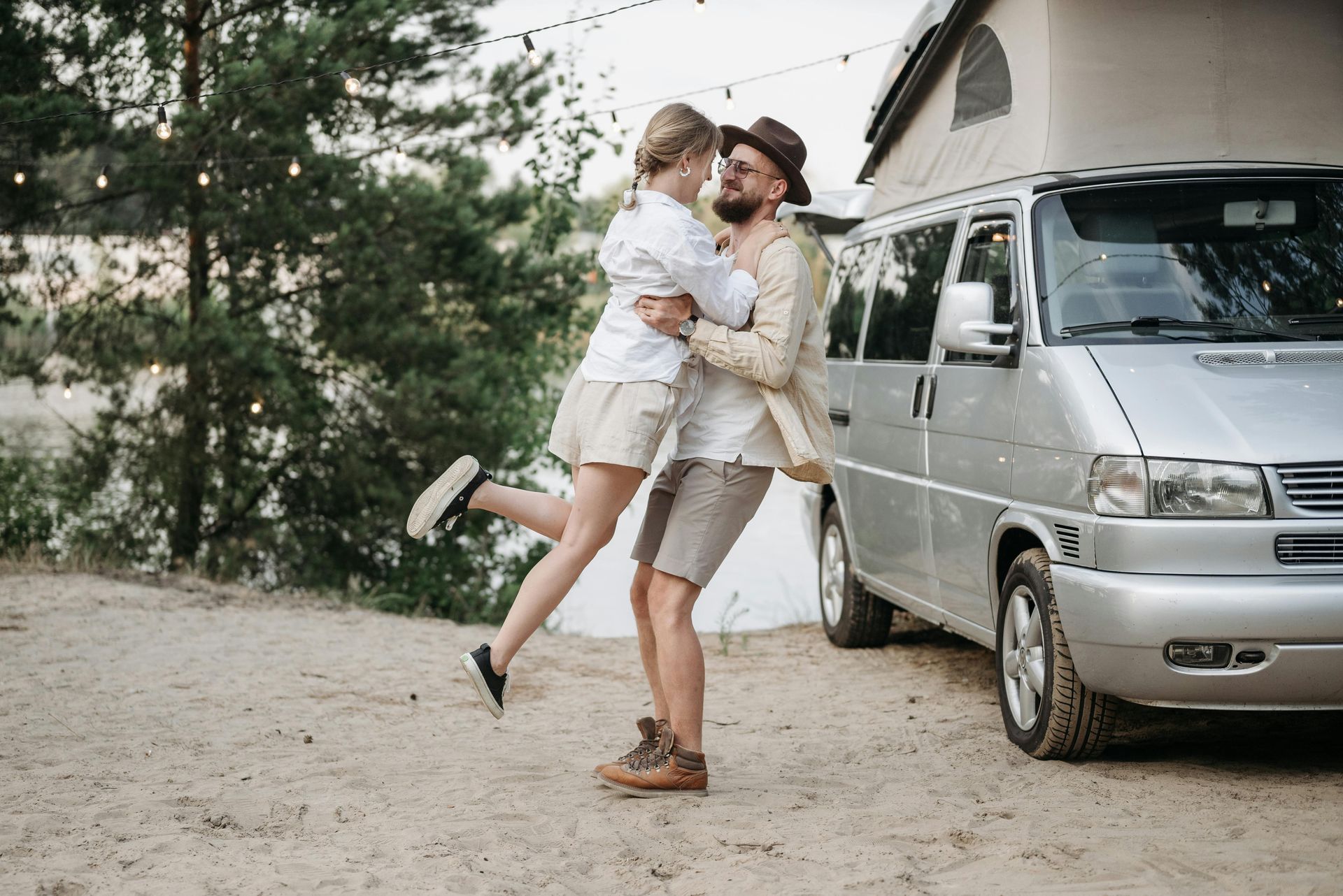 A man is holding a woman in his arms in front of a van.