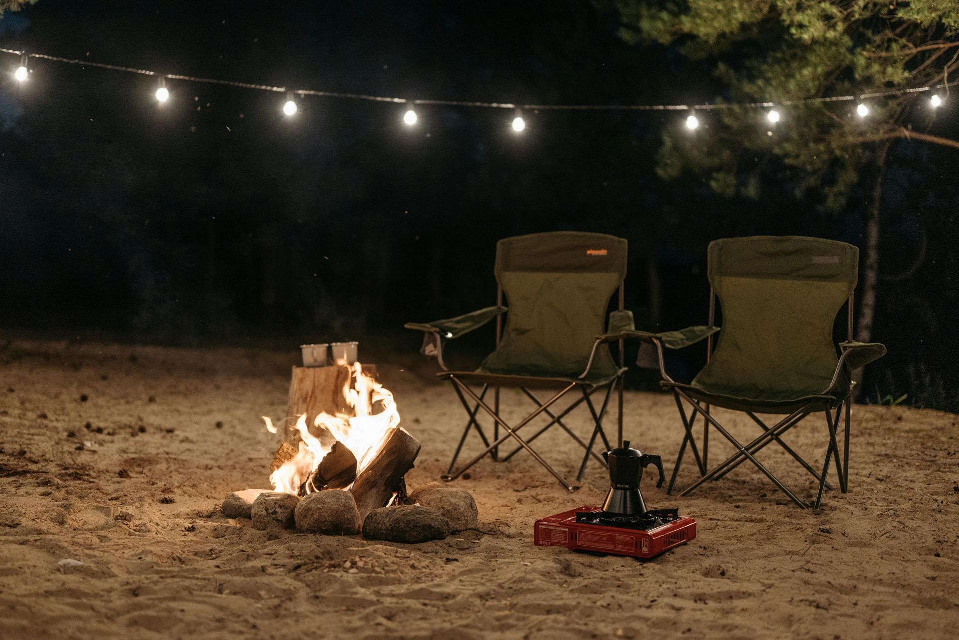 A red tent is sitting in the middle of a forest at night.