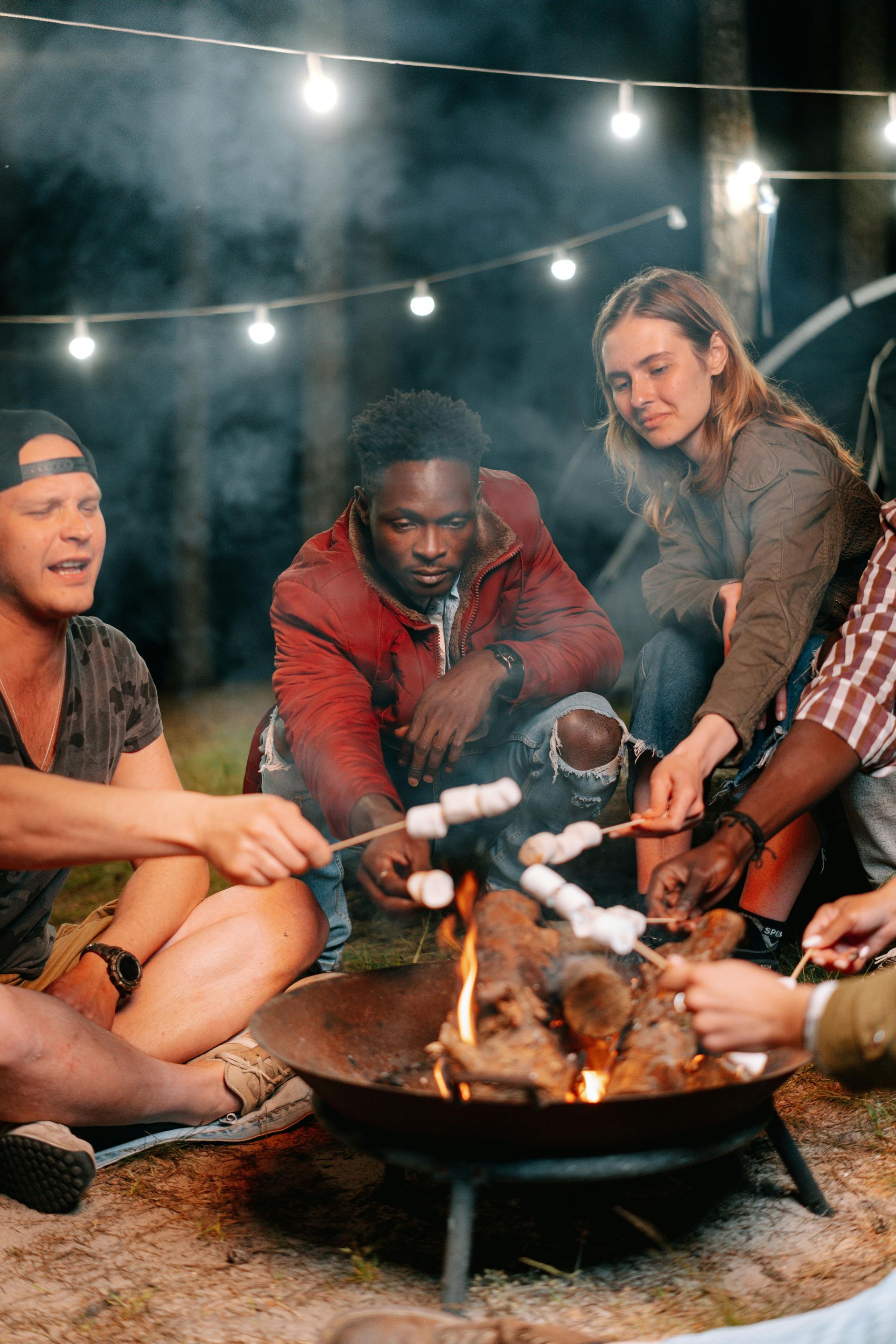 A group of people are roasting marshmallows over a fire pit.