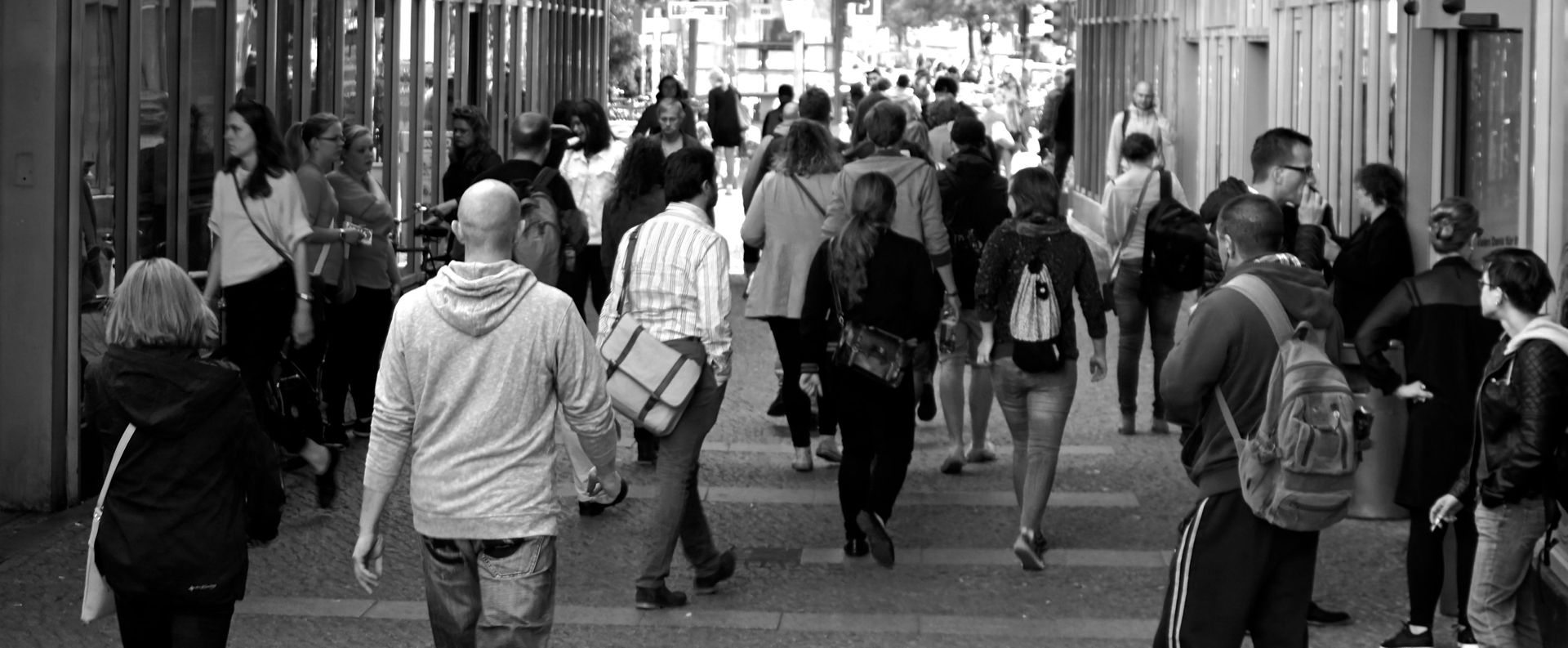 A black and white photo of a crowd of people walking down a street.