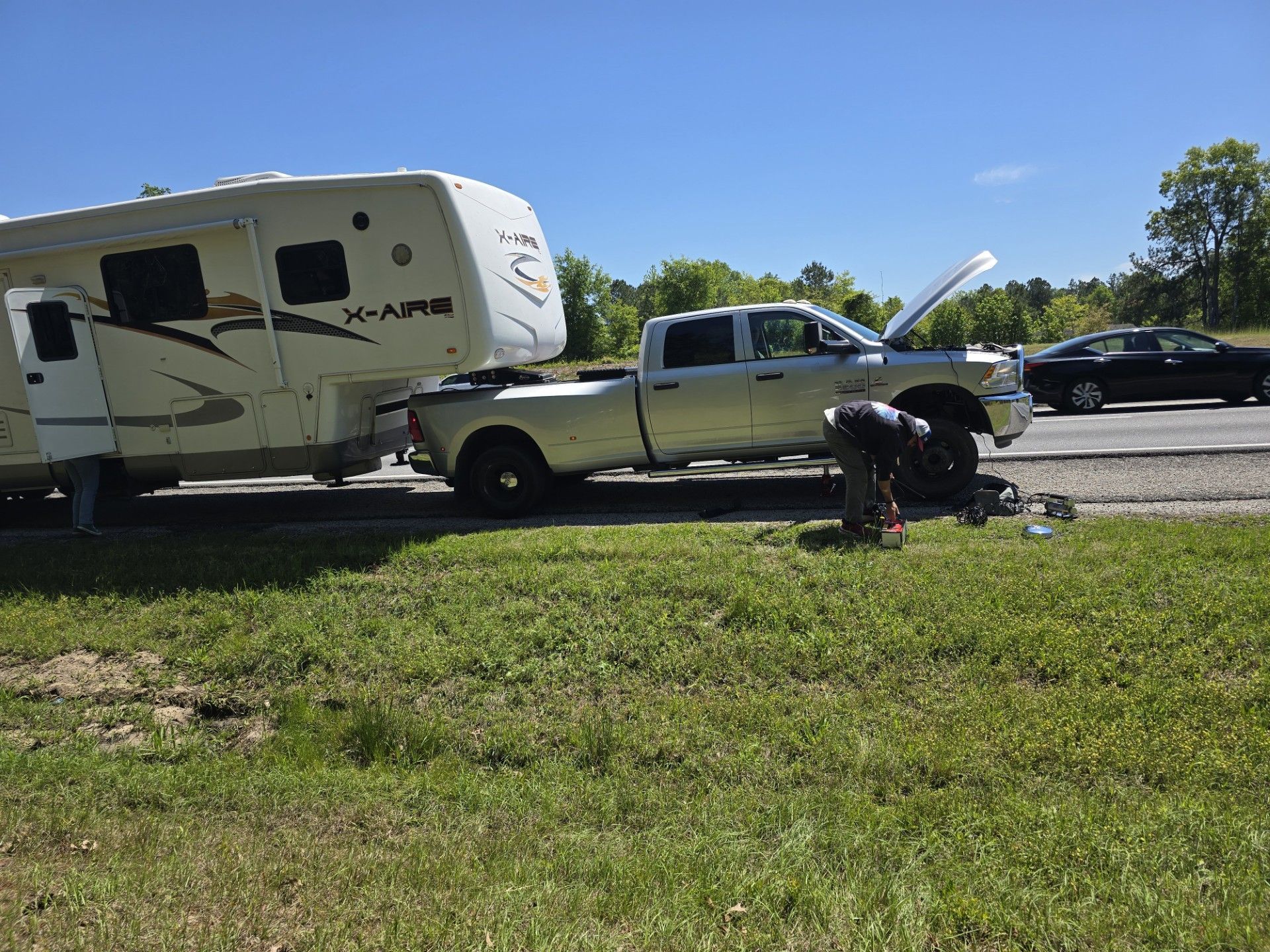 A man is working on a truck next to a trailer that says rv on it