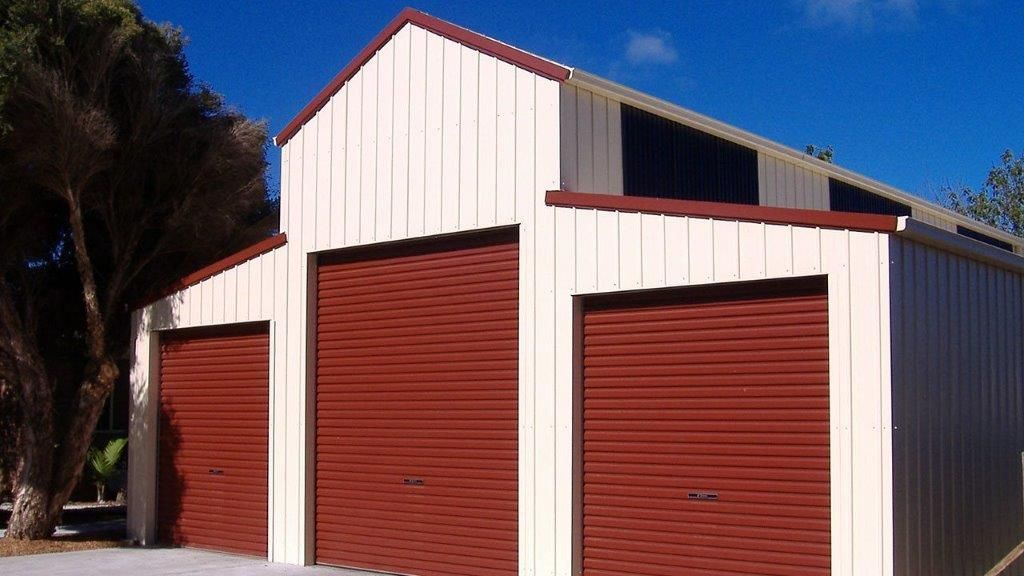 A white barn with three red garage doors  — More Than Garages Pty Ltd–Ranbuild Tamworth in Taminda, NSW