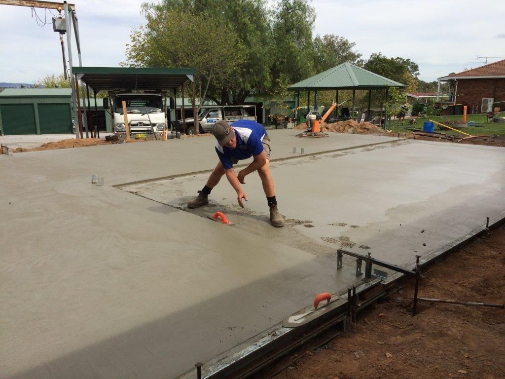 Worker smoothing wet concrete in an outdoor construction area — More Than Garages Pty Ltd–Ranbuild Tamworth in Taminda, NSW