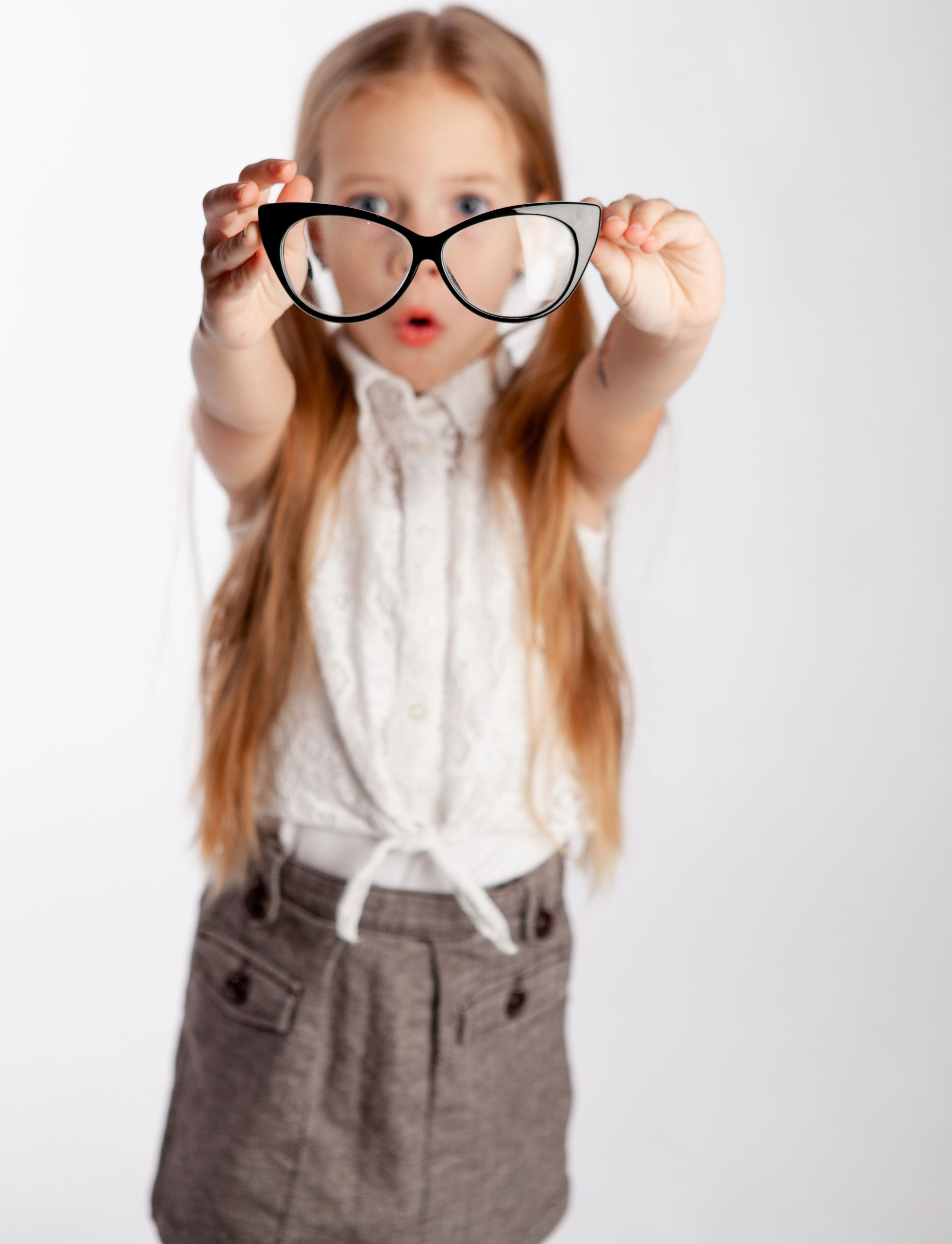 Famiglia che sceglie gli occhiali in un negozio di ottica. La madre indica, il figlio indossa gli occhiali, l'ottico aiuta.