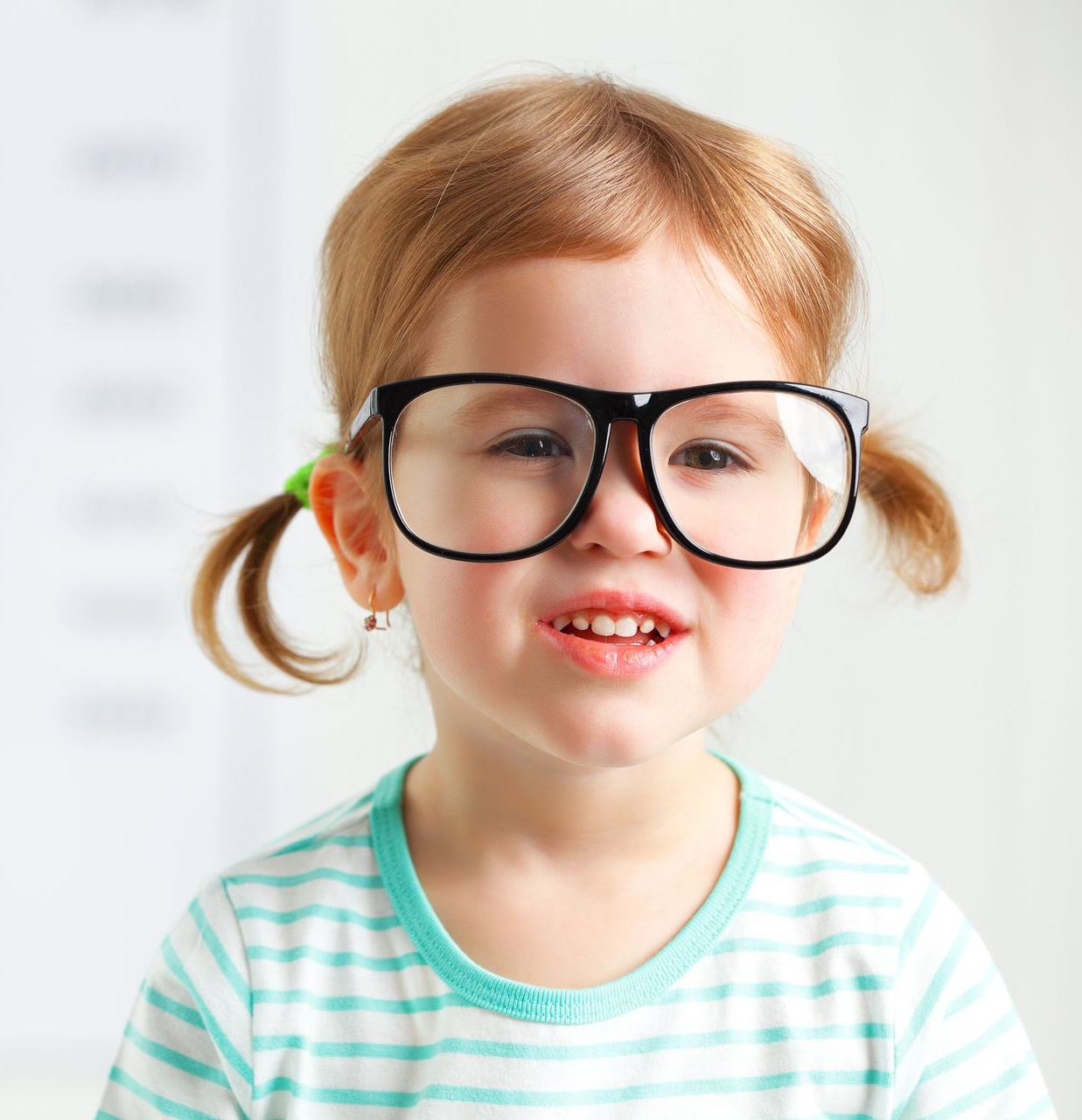 Famiglia che sceglie gli occhiali in un negozio di ottica. La madre indica, il figlio indossa gli occhiali, l'ottico aiuta.