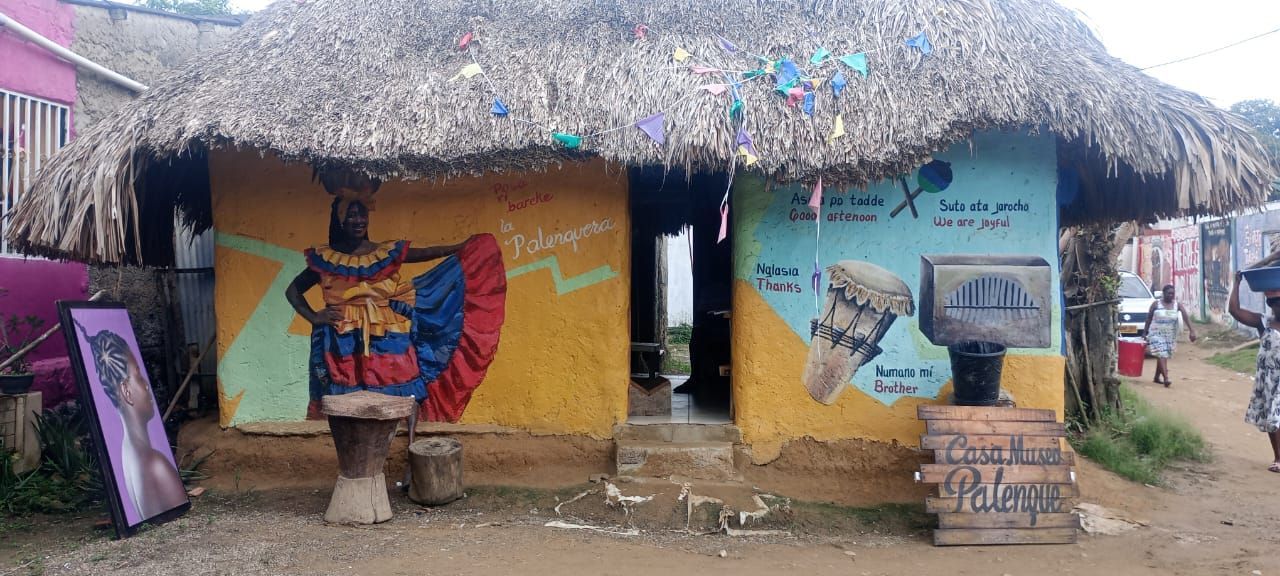 Un edificio con techo de paja con una pintura en el costado.