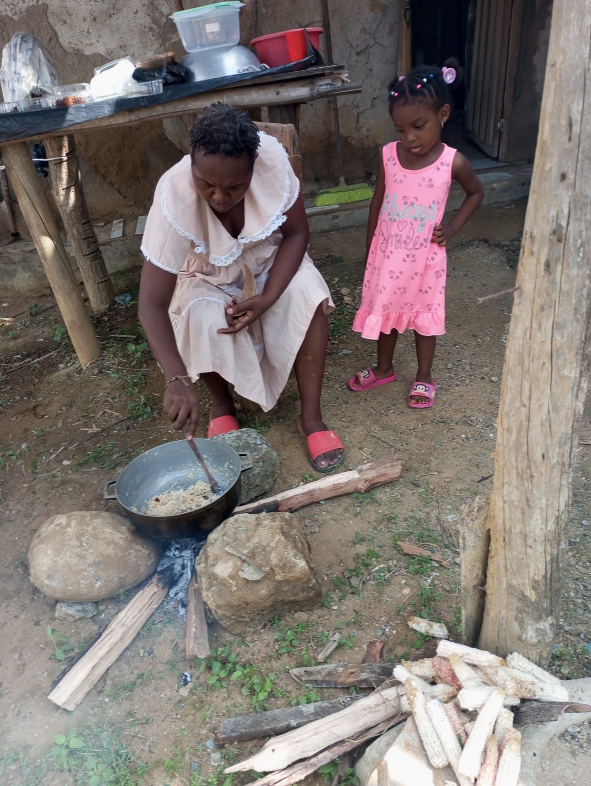 Una mujer y una niña están cocinando afuera en un fuego.