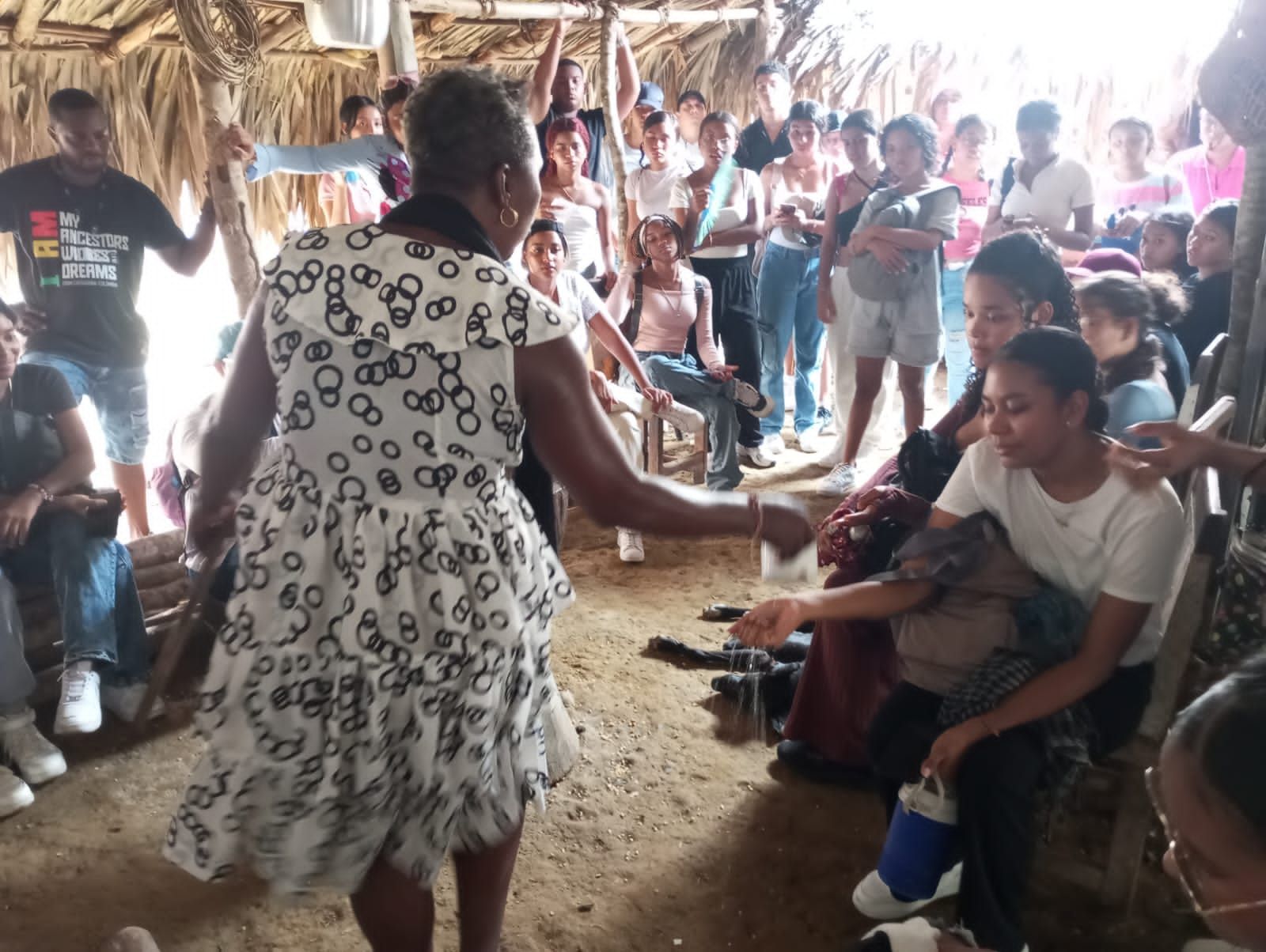Una mujer con un vestido blanco está bailando frente a una multitud.