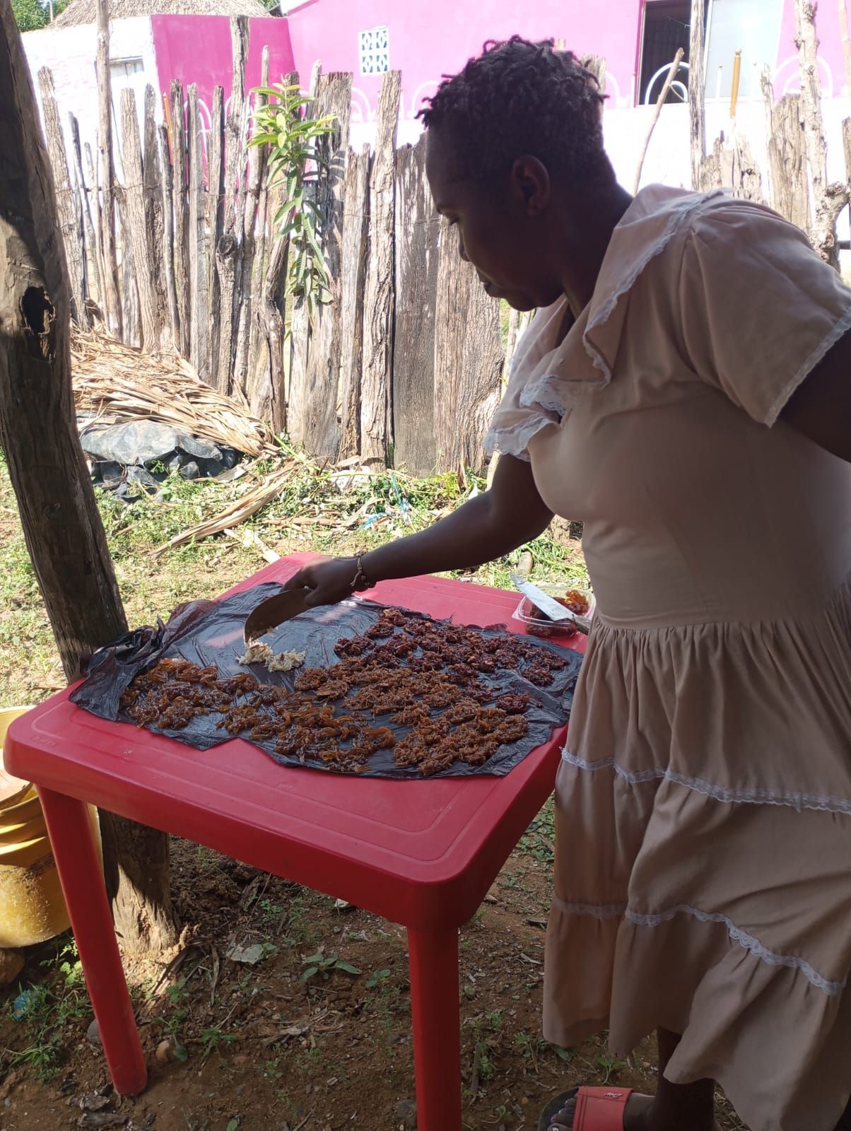 Una mujer con un vestido blanco está de pie junto a una mesa roja con comida.