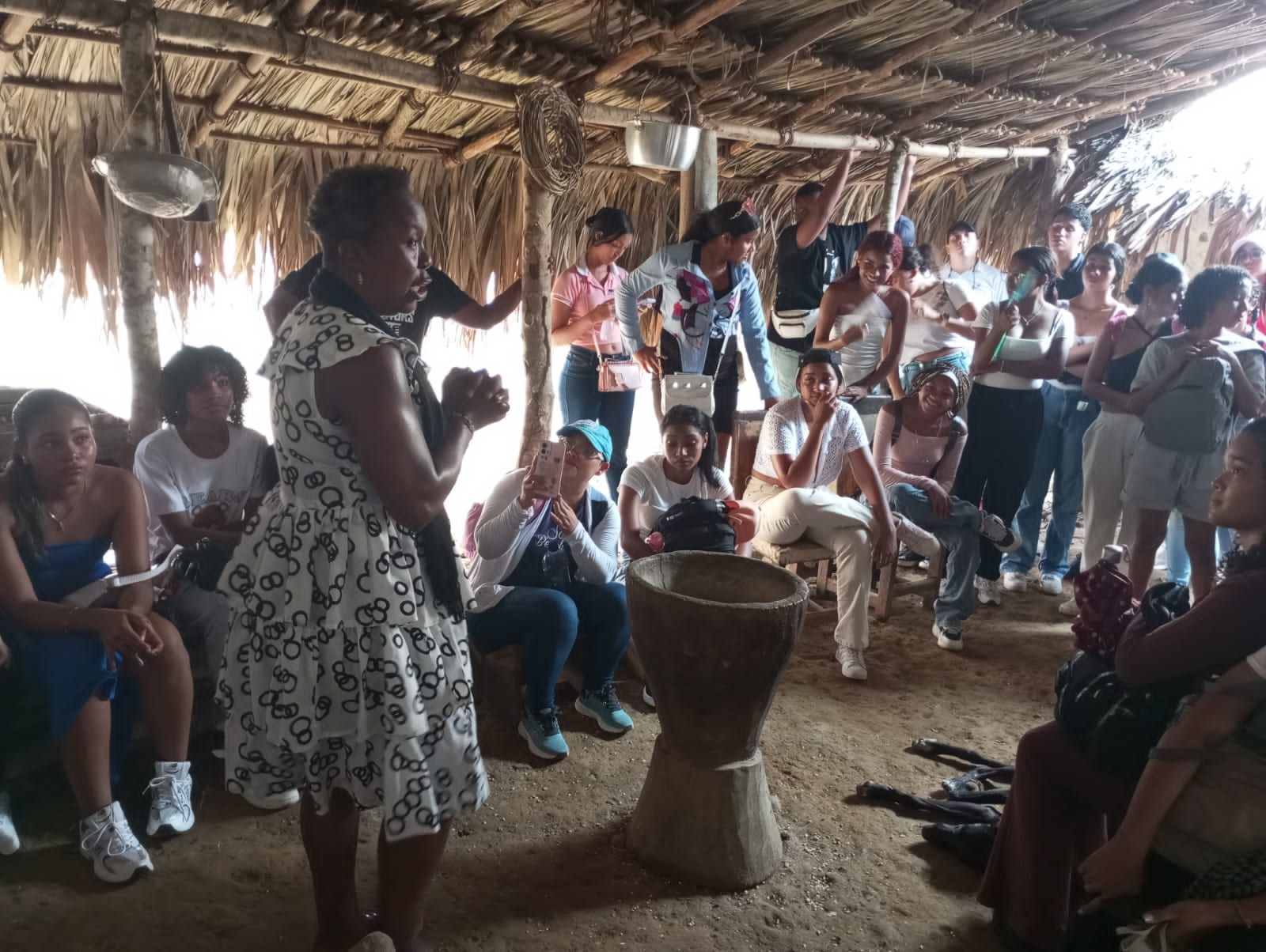 Una mujer con un vestido blanco está parada frente a un grupo de personas.