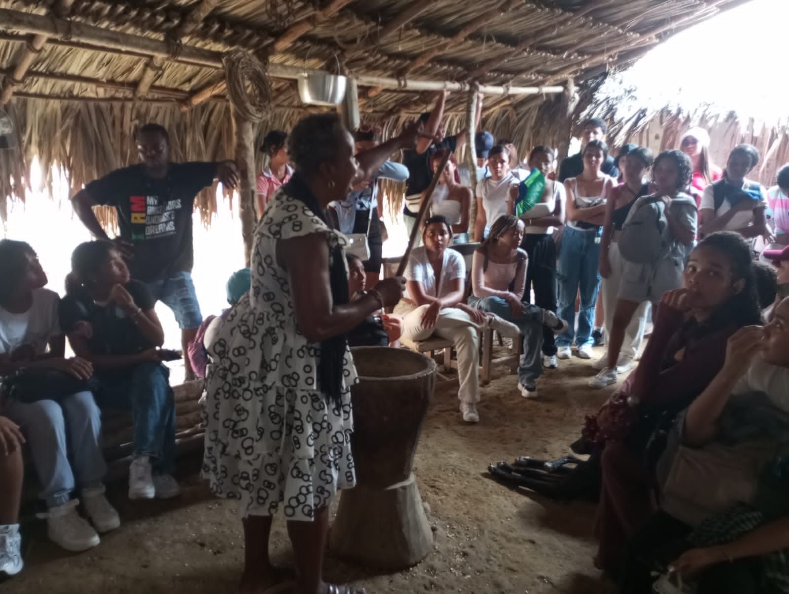 Una mujer está tocando un tambor frente a una multitud de personas.