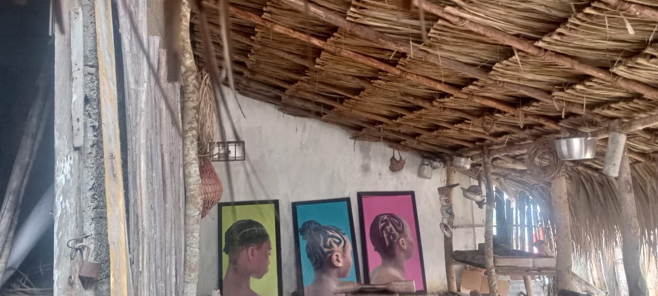 Una habitación con techo de paja y tres cuadros en la pared.