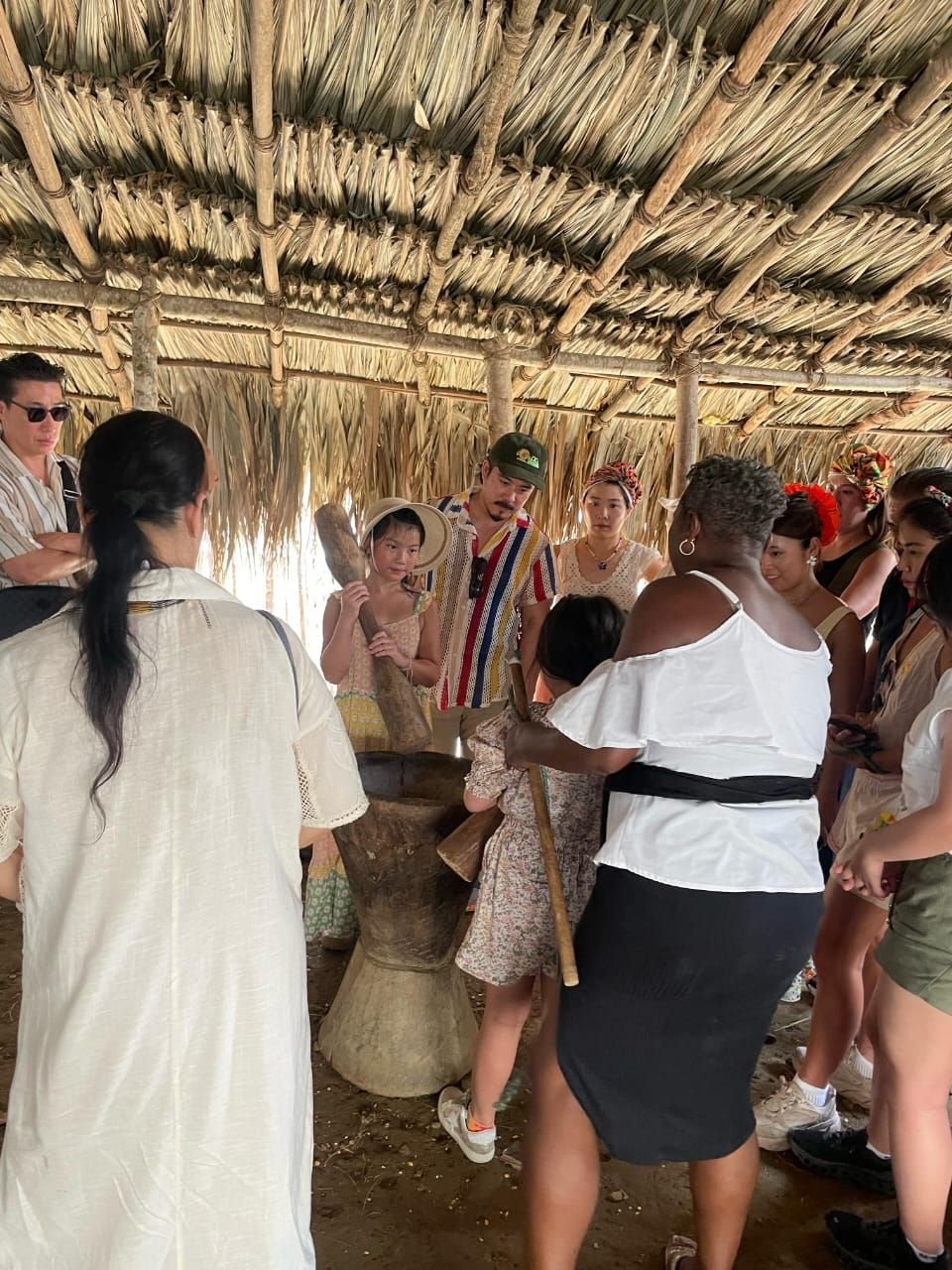 Un grupo de personas está de pie alrededor de una choza de paja.