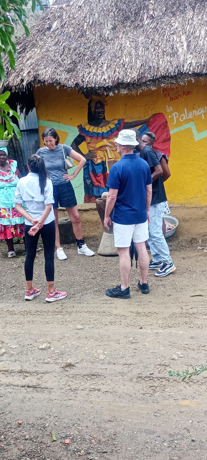 Un grupo de personas está de pie frente a una choza con techo de paja.