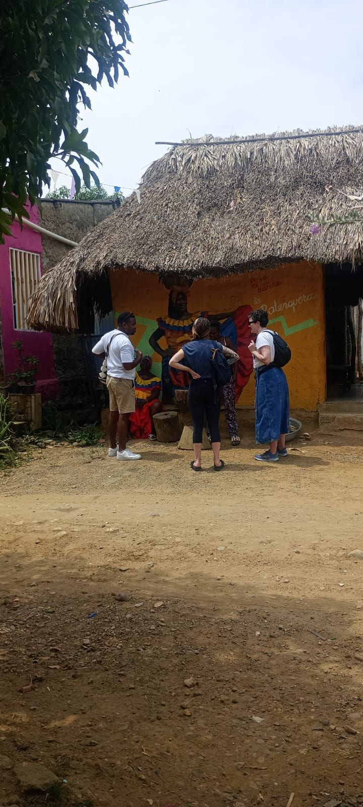 Un grupo de personas está de pie frente a una casa con techo de paja.