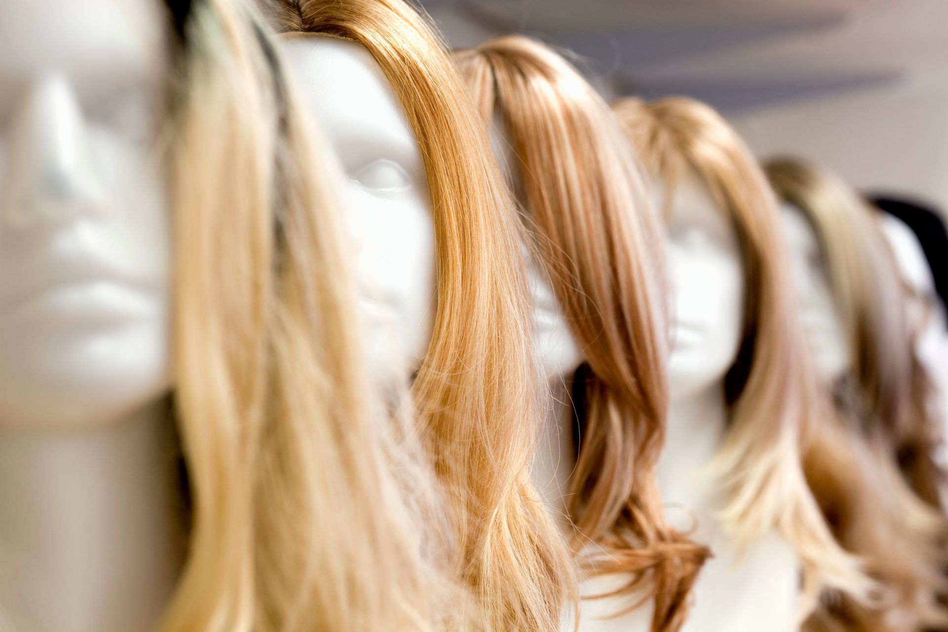 Mannequin heads with various shades of blonde and brown wigs.