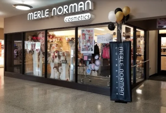 Person holding a blonde wig, brushing it in front of a mirror.