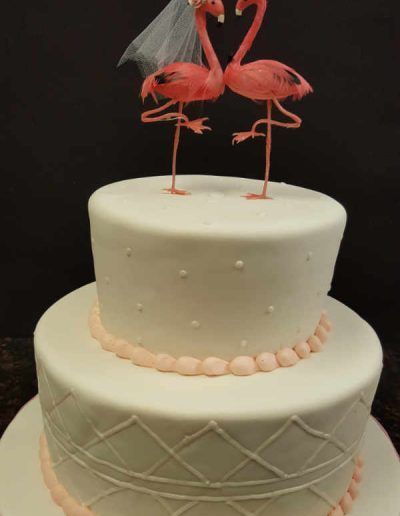 A wedding cake with flamingos on top of it