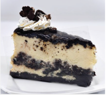 A slice of oreo cheesecake with whipped cream on top on a white plate.