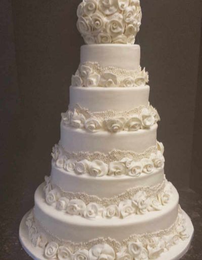 A white wedding cake with roses on top is sitting on a table.