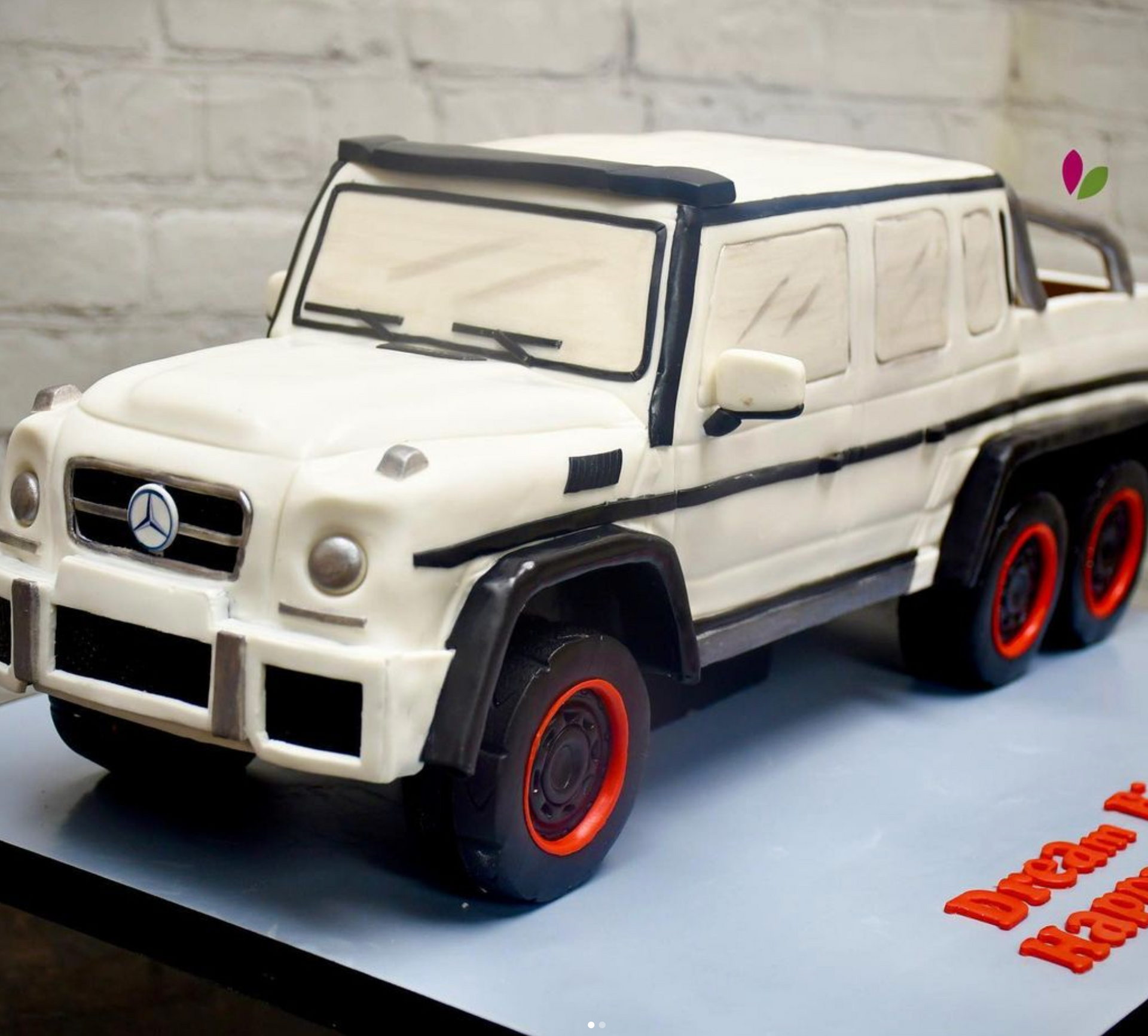 A cake in the shape of a mercedes with red wheels