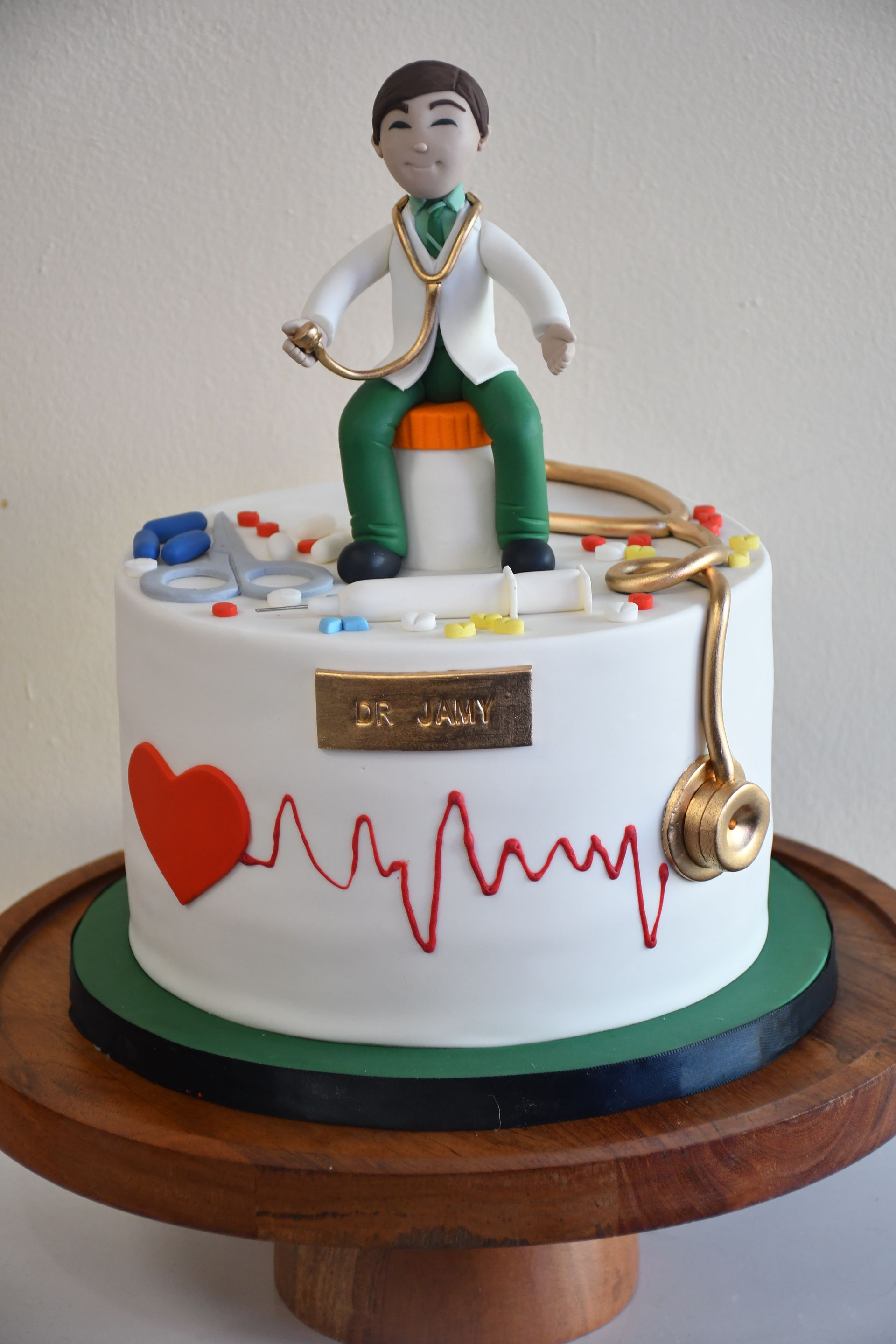 A cake with a doctor sitting on top of it