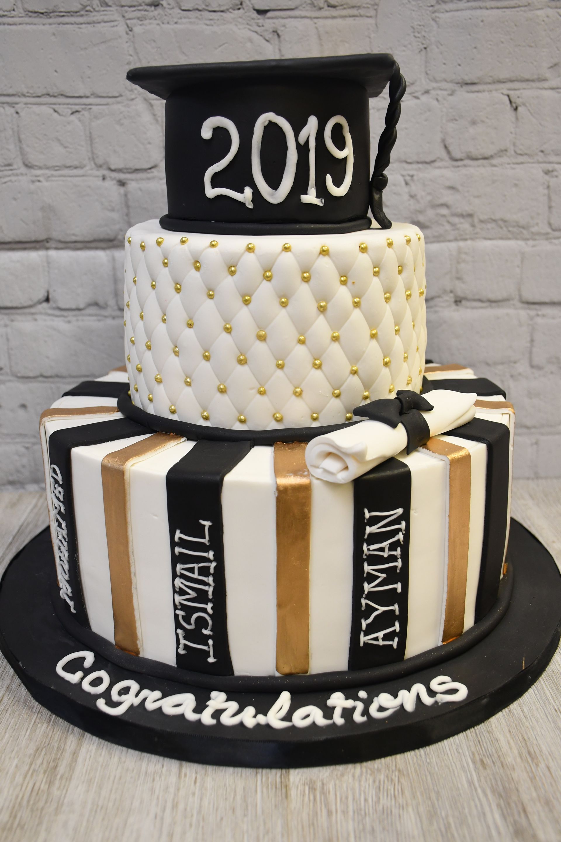 A black and gold graduation cake with the year 2019 on top