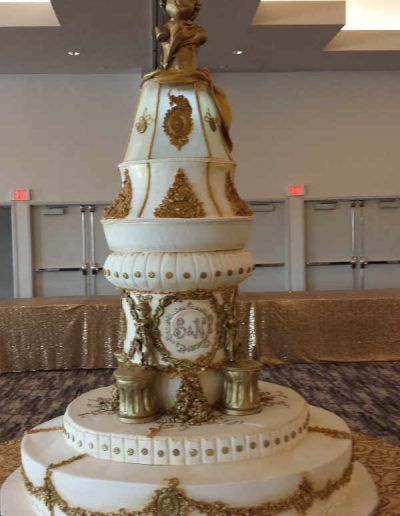 A white and gold cake with the letter a on it