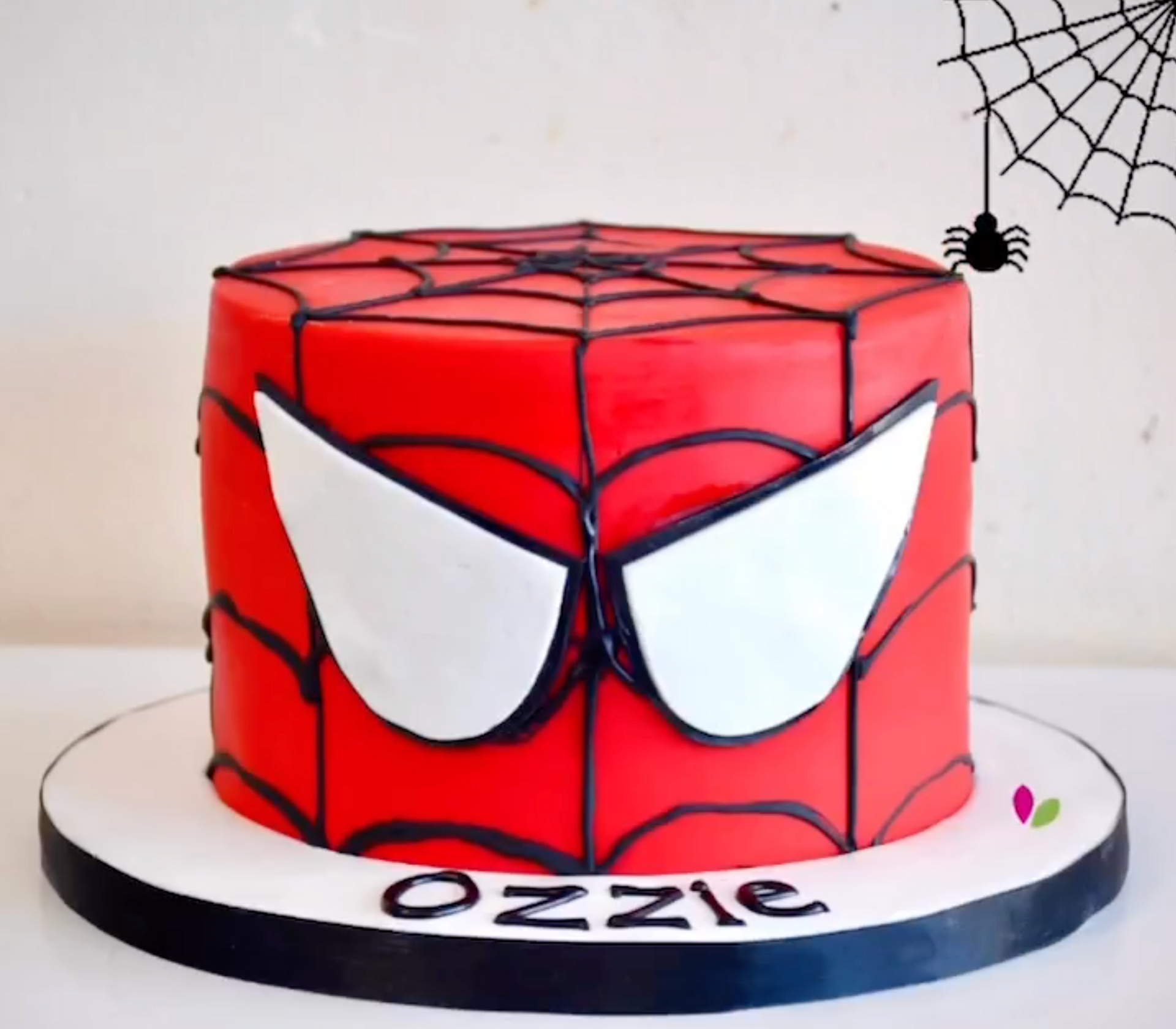 A spiderman cake with the name ozzie on it