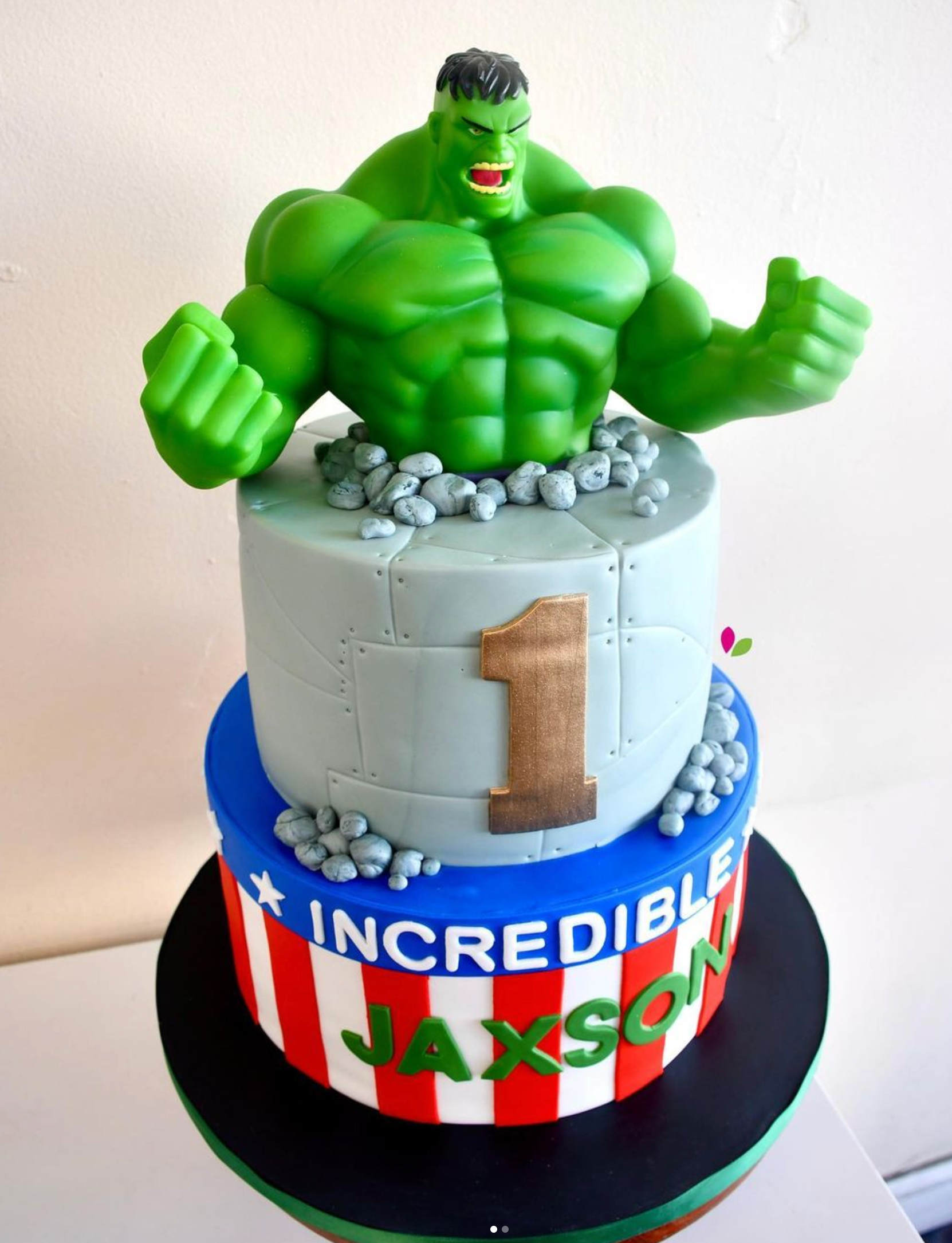 A cake with a hulk figurine on top that says incredible jaxson