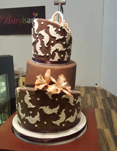 A three tiered chocolate cake with a bow on top