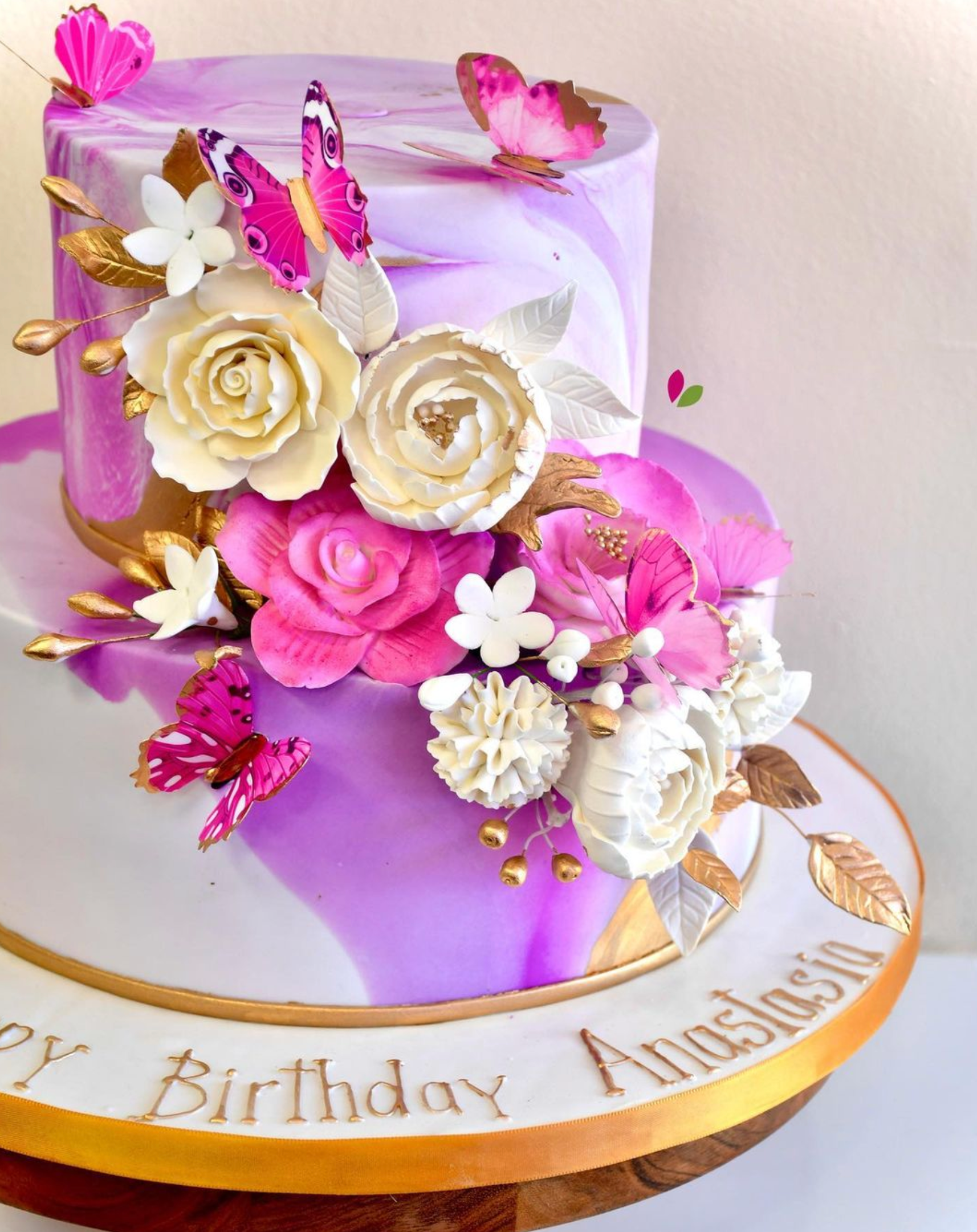 A purple birthday cake with pink flowers and butterflies