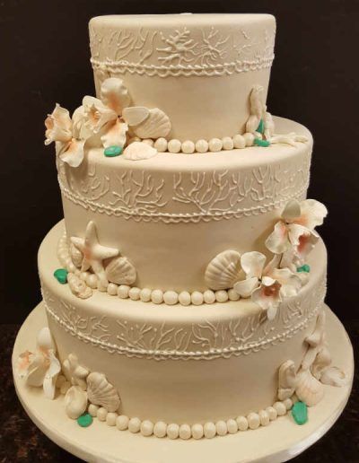 A white cake with seashells and flowers on it