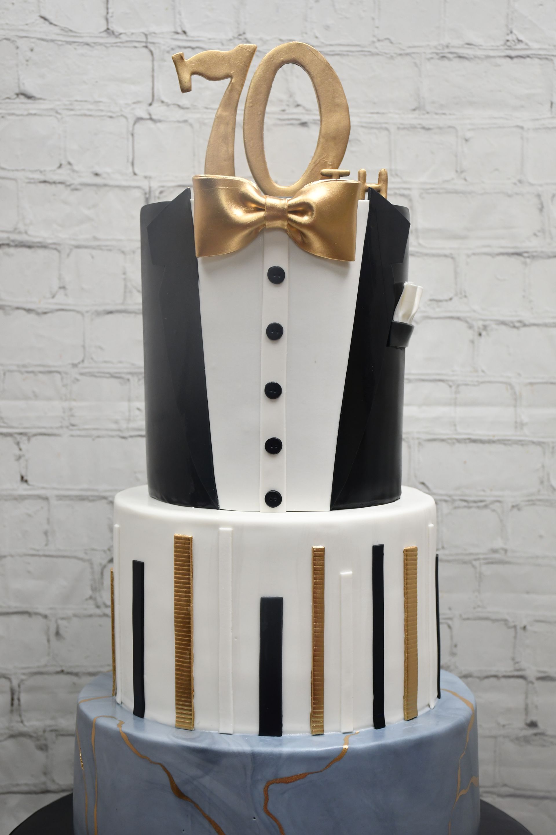 A black and white tuxedo cake with the number 70 on top