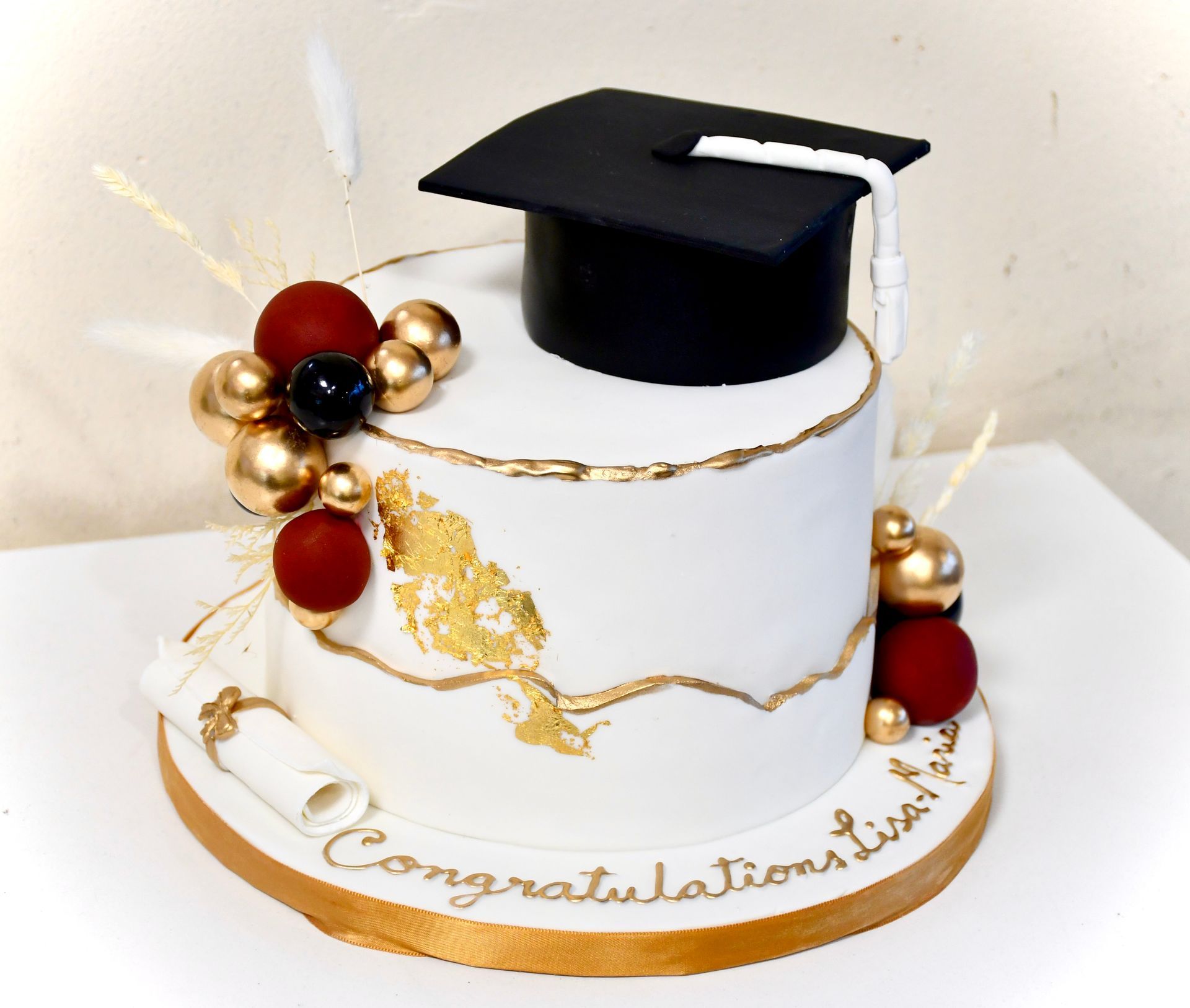 A white cake with a graduation cap and diploma on it