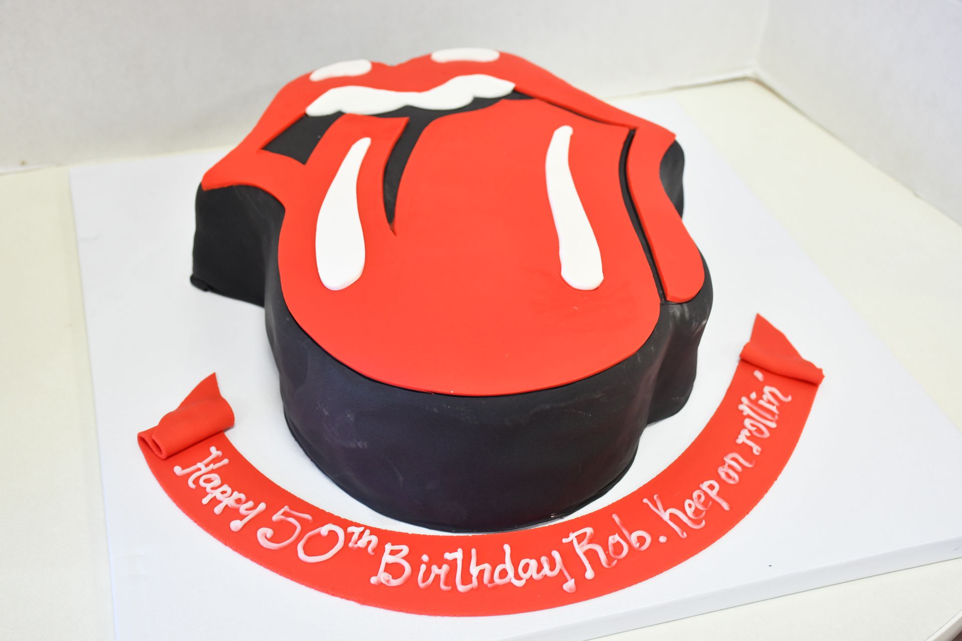 A 50th birthday cake with the rolling stones logo on it
