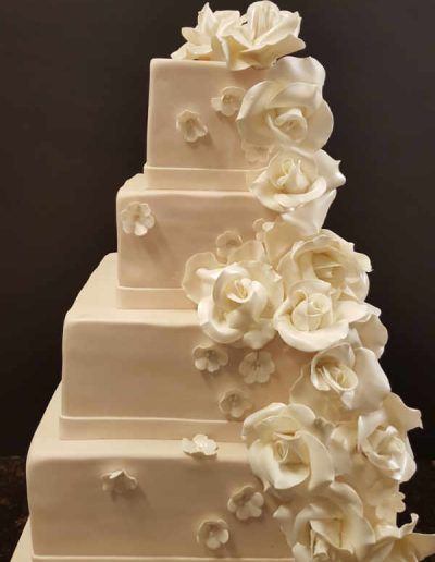 A white wedding cake with white roses on it