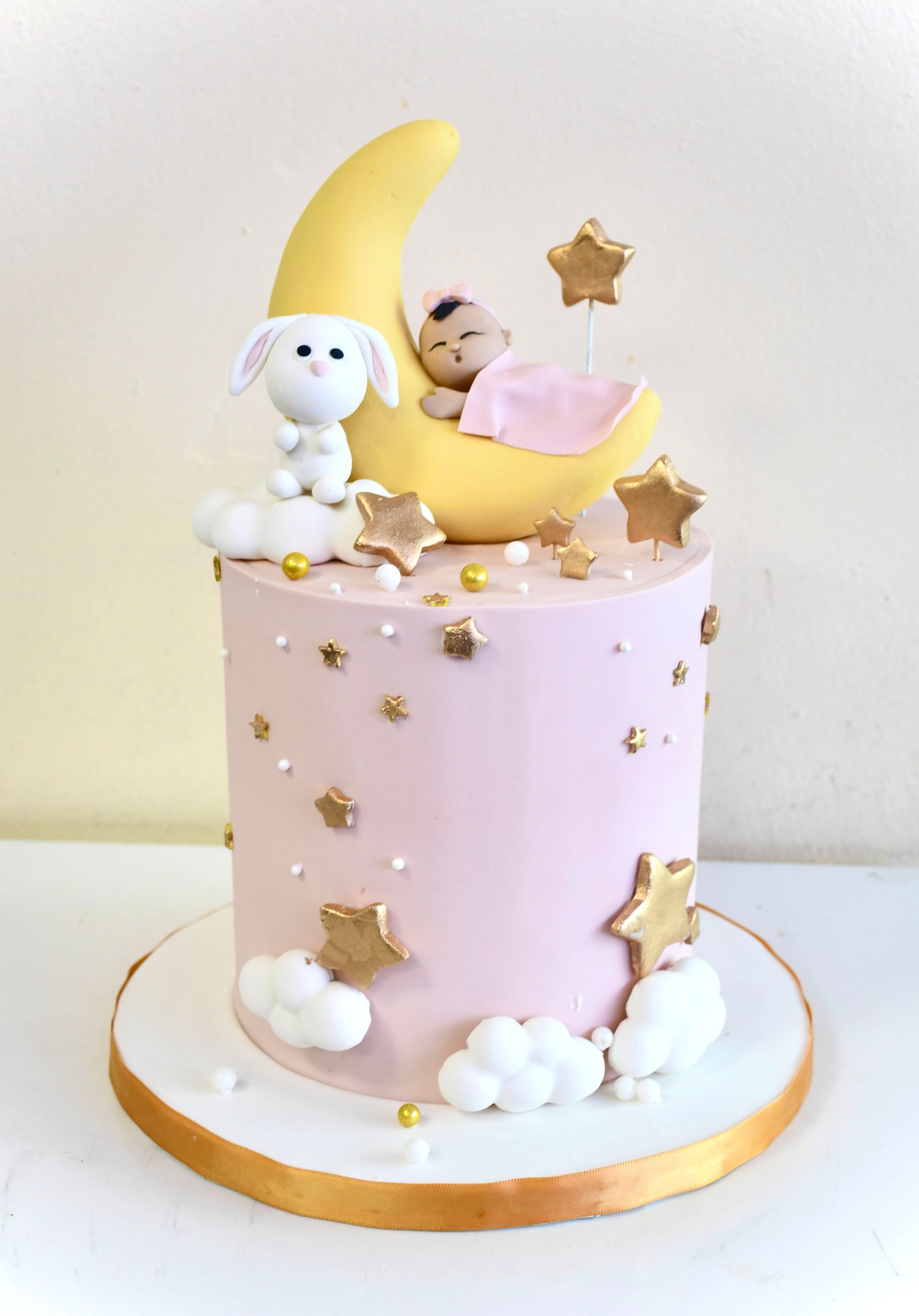 A pink cake with a baby sleeping on the moon