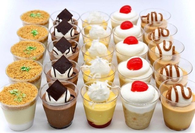 A variety of desserts in plastic cups on a table