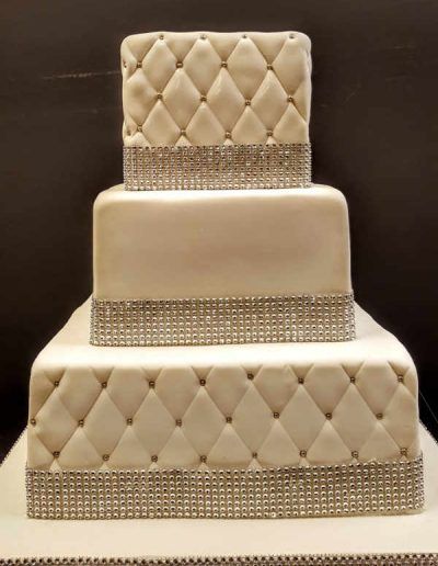 A white wedding cake with a quilted pattern and rhinestones