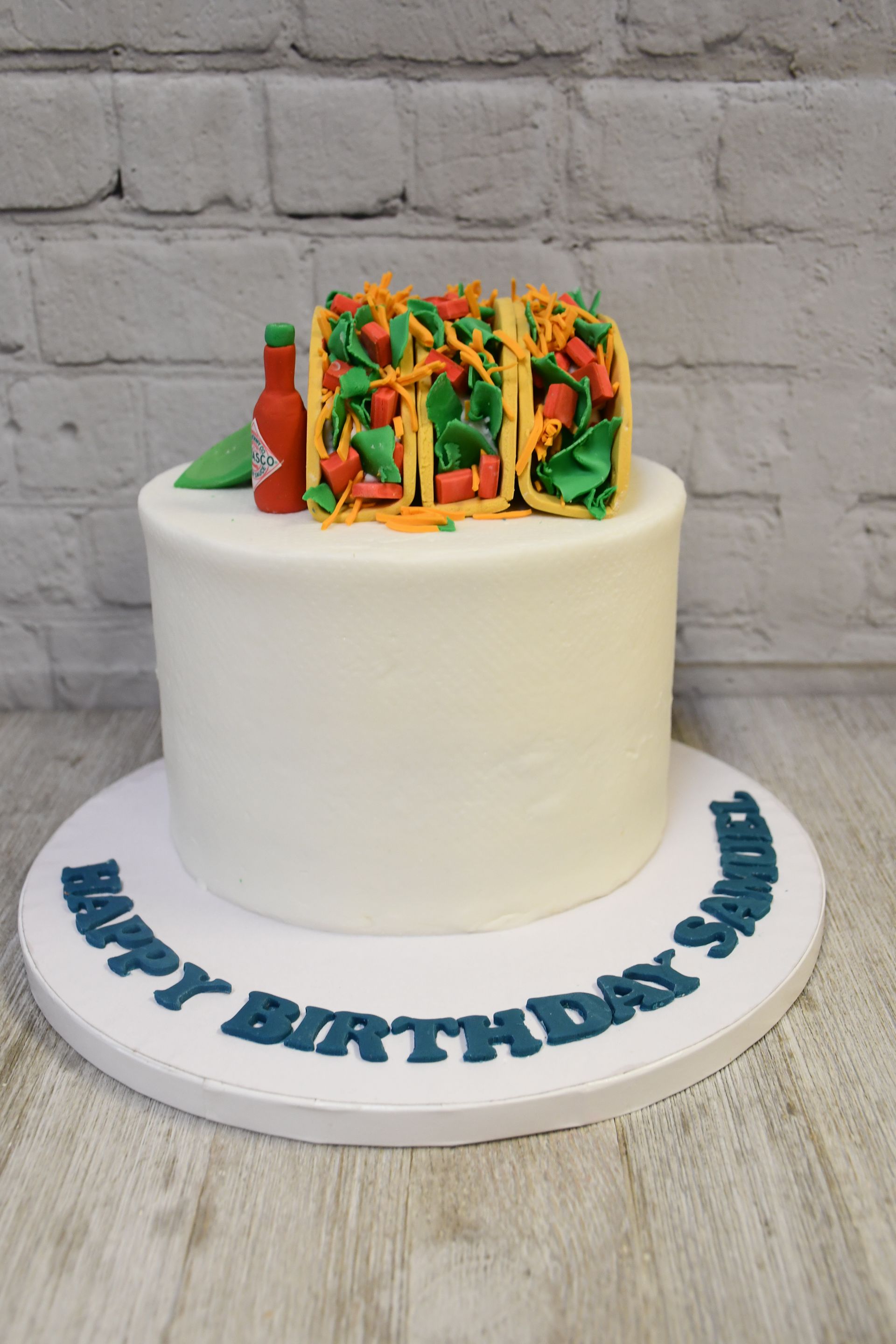 A birthday cake with tacos and a bottle of salsa on top