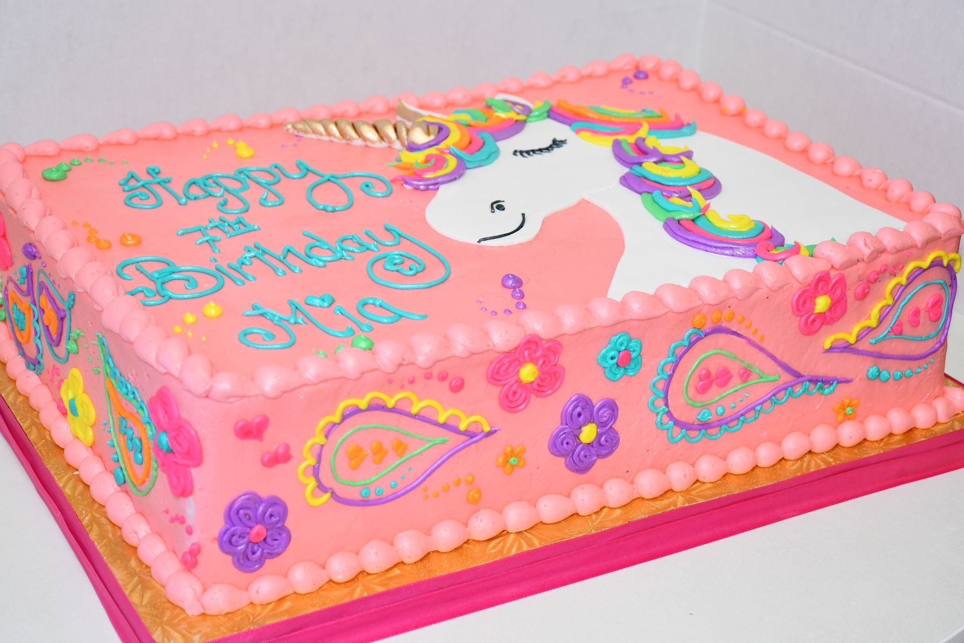 A pink birthday cake with a unicorn on it