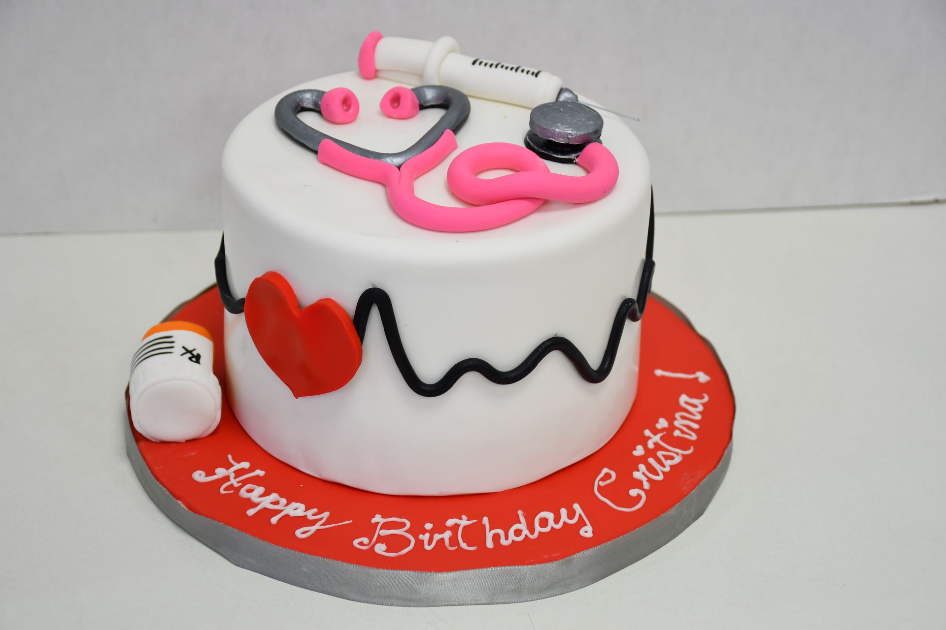 A birthday cake with a stethoscope and syringe on it