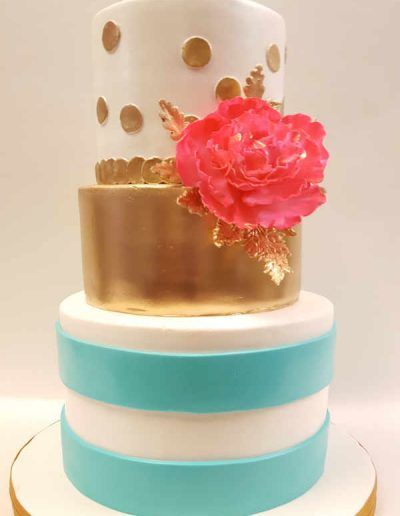 A three tiered wedding cake with a pink rose on top.