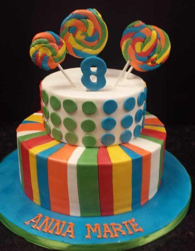 A colorful birthday cake for anna marie with lollipops on top